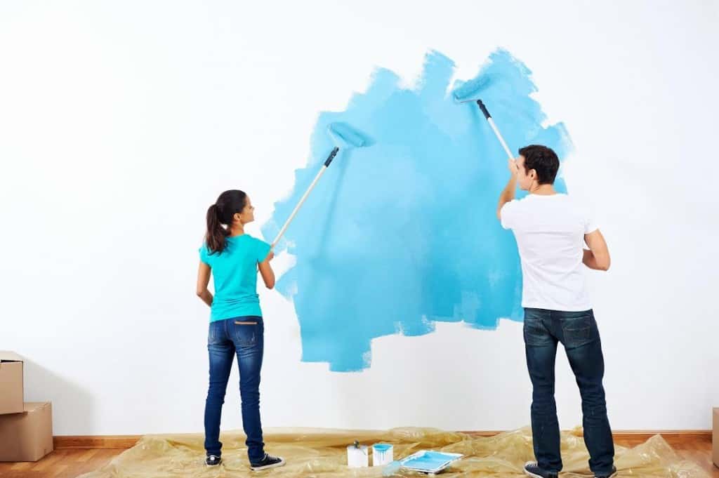 couple painting new home together with blue color happy and carefree relationship